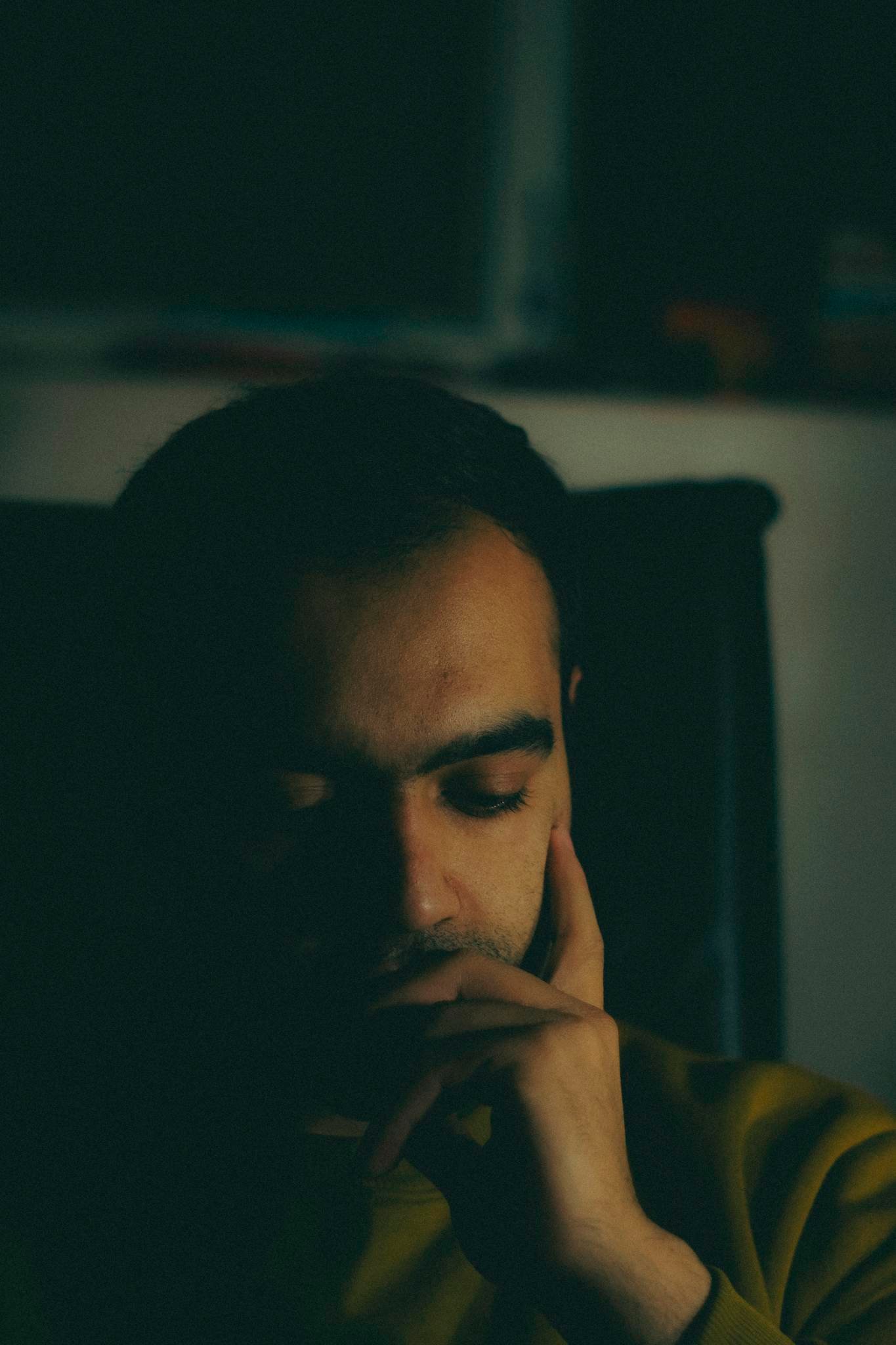 A close-up view of a man deep in thought, face partially illuminated, conveying introspection.